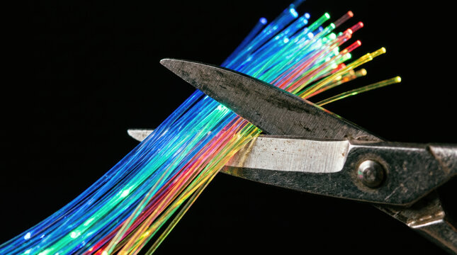 Fiber optic cable cut with scissor tech layoffs concept isolated on black background showing severed internet connection and network disruption