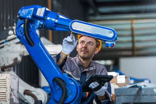 Industrial engineers inspecting and calibrating robotic arm systems in smart factory. automation technology, preventive maintenance, quality control, manufacturing solutions.