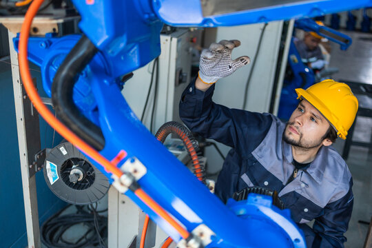 Industrial engineers inspecting and calibrating robotic arm systems in smart factory. automation technology, preventive maintenance, quality control, manufacturing solutions.