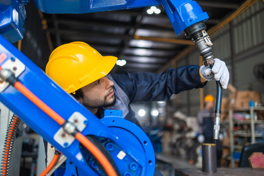 Industrial engineers inspecting and calibrating robotic arm systems in smart factory. automation technology, preventive maintenance, quality control, manufacturing solutions.