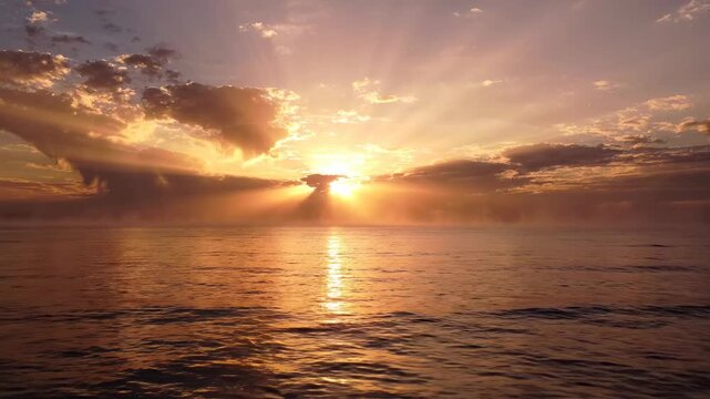 Golden hour sunrise over calm ocean water with dramatic sunbeams breaking through clouds, serene atmosphere