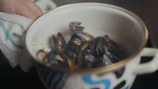 Close up of cooked mussels in a white ceramic pot with blue accents