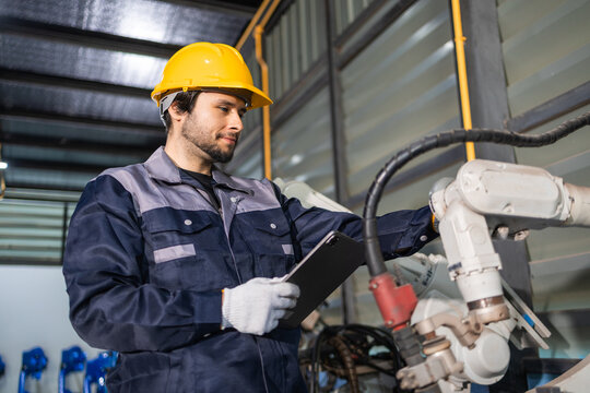 Industrial engineers inspecting and calibrating robotic arm systems in smart factory. automation technology, preventive maintenance, quality control, manufacturing solutions.
