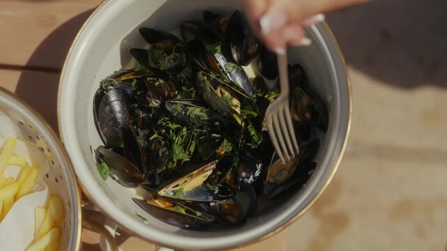 Steamed mussels with parsley and fries served in a ceramic bowl