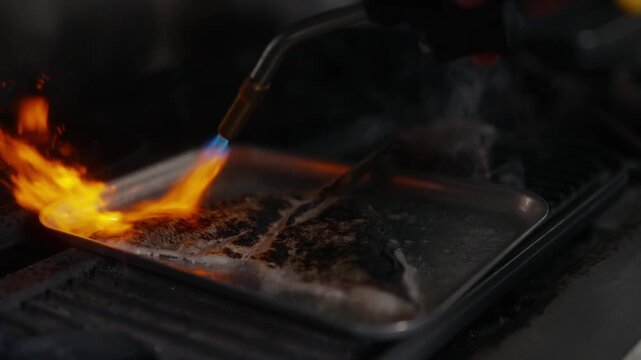 Chef uses torch to caramelize sugar on dessert in a restaurant kitchen