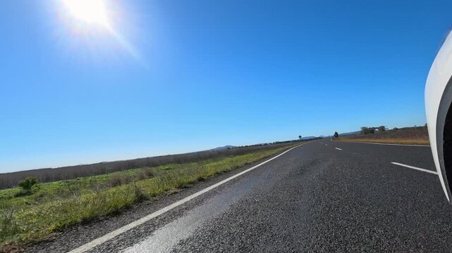 Driving on Asphalt Highway Through Rural Australian Outback Under Blue Sky