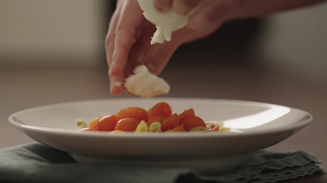Slow motion making pesto penne pasta with mozzarella and tomatoes in deep plate closeup