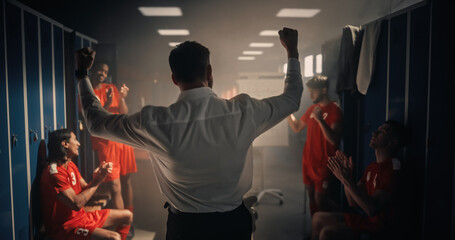 Obraz premium Back View of a Soccer Coach in a White Shirt Raising Both Fists Triumphantly as Four Multiethnic Footballers in Red Uniforms Clap and Cheer in a Moody Blue-locker Changing Room
