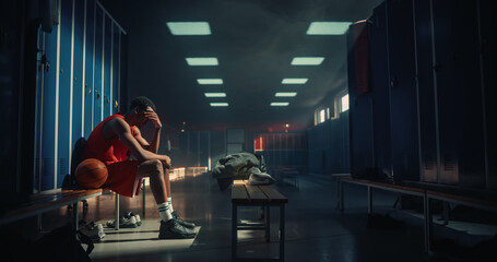 Naklejka premium Upset African American Male Basketball Player Sitting Alone on Locker Room Bench With Hand on Face After Losing Championship Tournament Match, Sad Young Man Athlete Feeling Defeat, Sport