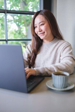 Vertical portrait image of a woman working on laptop computer in cafe
