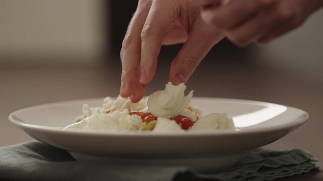 Slow motion making pesto penne pasta with mozzarella and tomatoes in deep plate closeup