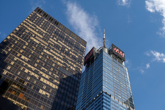 Low angle view of modern skyscrapers in Midtown Manhattan, featuring the iconic 4 Times Square building with the H&M logo against a blue sky, New York City, USA, June 20, 2026.