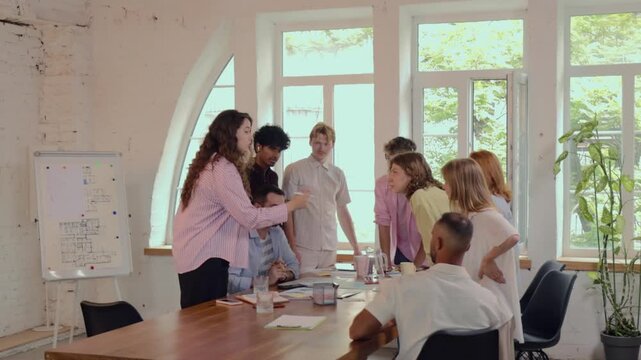 Diverse office team joining hands after successful collaborative planning session. Concept of team unity, shared achievement, employee motivation.