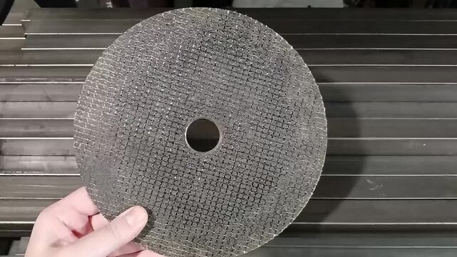 Hand holding an abrasive cutting disc for metal used by grinders