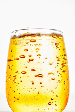 Sparkling golden drink with carbonated bubbles in glass close up
