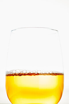 Golden beer with foam in clear glass on white background