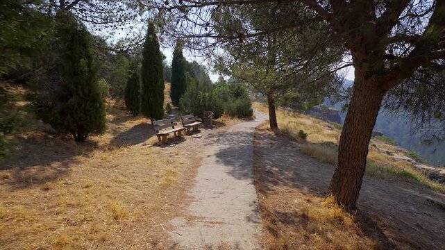 Shaded woodland footpath with benches among pine trees at a viewpoint above Cuenca Spain