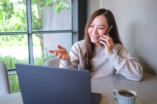Portrait image of a businesswoman talking on mobile phone while working on laptop computer