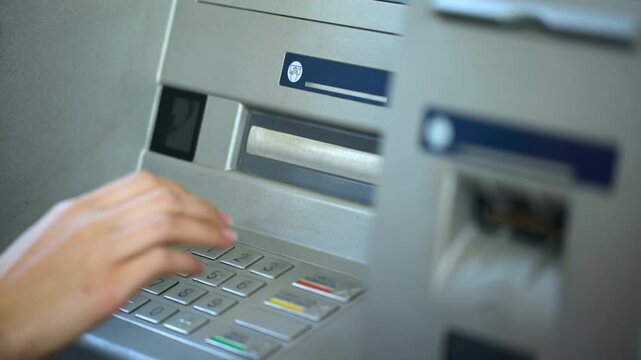 Woman pressing correction button and inserting her pin code on keyboard of ATM machine for secure banking transaction in 4K Ultra HD footage
