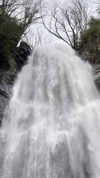 Low angle vertical view of a wide waterfall stream.
