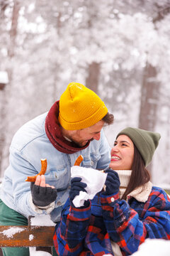 Couple taking a snack break while spending snowy winter day outdoors in nature
