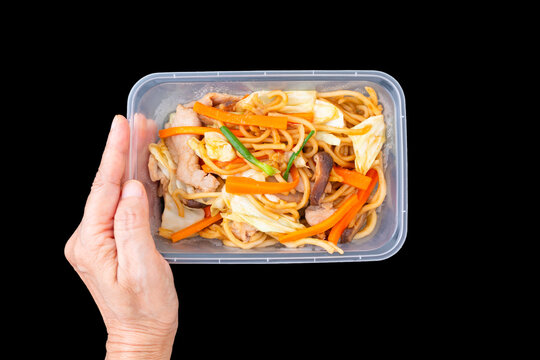 hand hold take away food, yakisoba  or Japanese stir-fried noodles, isolated on black background including clipping path