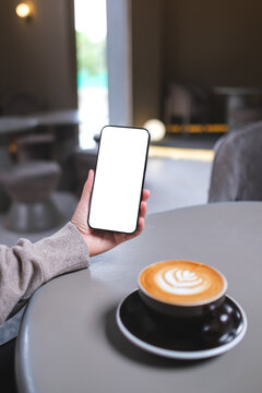 Vertical mockup image of a woman holding mobile phone with blank desktop screen in cafe