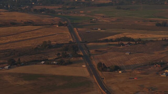 Sunset aerial of rural Midvale Idaho landscape with dirt road through farmland with golden light