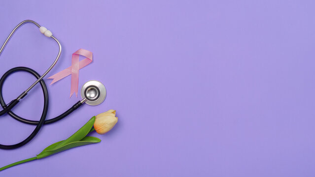 Breast cancer awareness concept with pink ribbon stethoscope and tulip on purple background