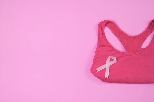 Breast cancer awareness concept with pink ribbon on sports bra over pink background