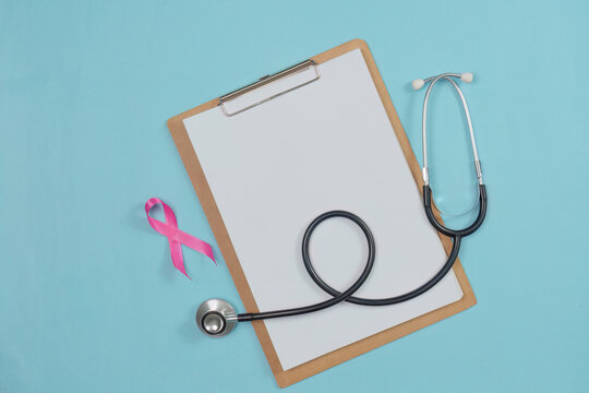 Breast cancer awareness concept with pink ribbon stethoscope and clipboard on blue background