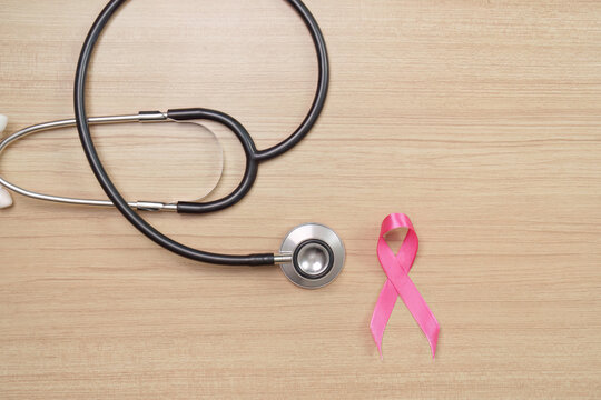 Breast cancer awareness concept with pink ribbon and medical stethoscope on wooden desk