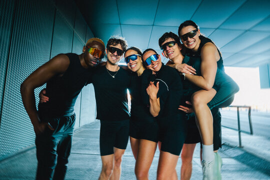 Running friends posing together outdoors in playful fitness group portrait