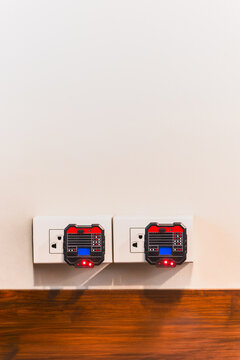 Two digital socket testers plugged into wall outlets to check electrical wiring.