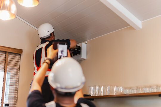 Unidentified electrician inspecting an electrical breaker box panel.