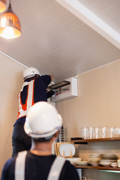 Unidentified electrician inspecting an electrical breaker box panel.