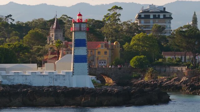 Santa Marta Lighthouse with the Museu Condes de Castro Guimar&atilde;es overlooking the Atlantic coastline in Cascais, Portugal, during golden hour.