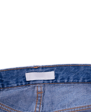 Blue denim jeans with a customizable white label on the waistband against a white background