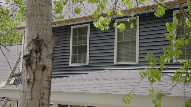 Slow motion pan from a white birch tree revealing newly installed windows and siding