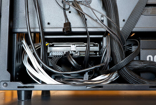 Internal view of power supply cabling, hard drive cage, and cable management routing inside desktop PC case
