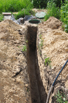 Water line trench excavation with underground pipeline and inspection manhole