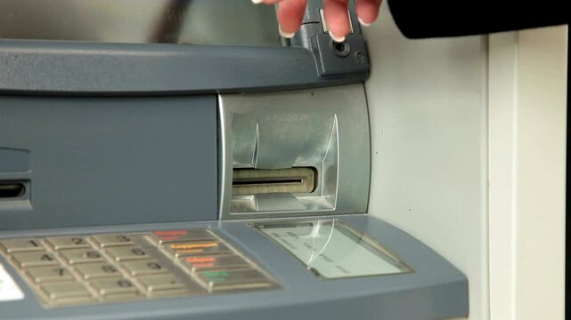 Withdrawing money from ATM machine with close up of hand inserting debit card and taking cash from automated teller in 4K Ultra HD footage
