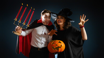 Obraz premium Happy Couple in Halloween Costumes with Pumpkin, Dracula and Witch