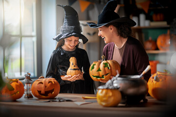 Obraz premium Mother and Daughter in Witch Costumes Carving Pumpkins for Halloween