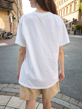 Woman wearing a plain white t-shirt and beige shorts on a European street