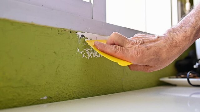 hand applying wall filler with putty knife to repair damaged surface during interior renovation and restoration work