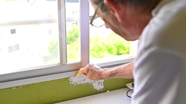 Man repairing interior wall with putty knife during home renovation, wall restoration and residential improvement project
