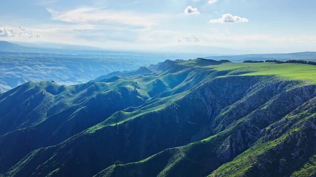 Aerial view of undulating green ridges and deep mountain ravines in Kalajun Grassland, Xinjiang, China.