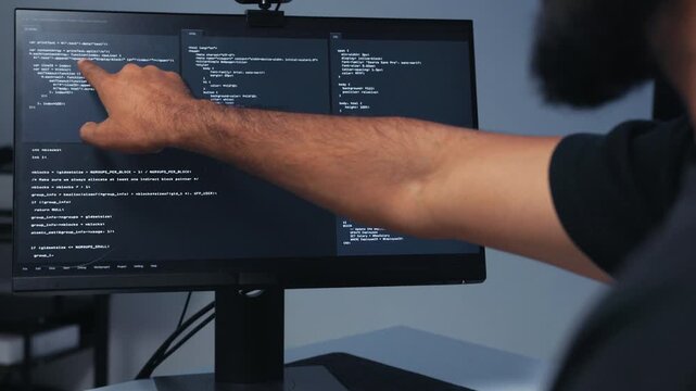 Portrait of Professional Indian Male Software Developer, Computer Programmer working on computer typing on keyboard, writing code and Pointing at Monitor, Reviewing and Checking Code on Screen.