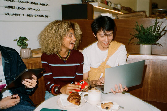 Gen Z friends collaborating on laptop in cafe